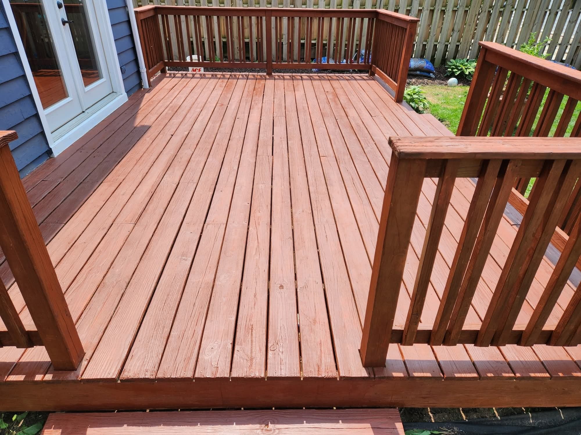 Same backyard wood deck refinished in a rich mahogany stain with even, sealed planks by Fortoso Painting in Portage, Michigan